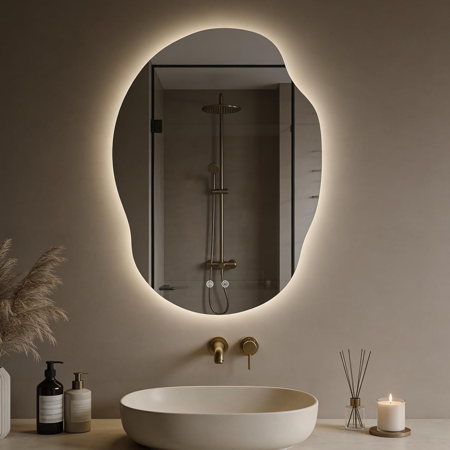 Asymmetrical backlit bathroom mirror above a vessel sink with gold wall faucet and toiletries on the counter.