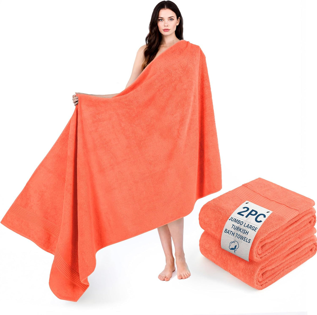 Model wrapped in a large coral towel standing next to a folded stack of coral bath towels.