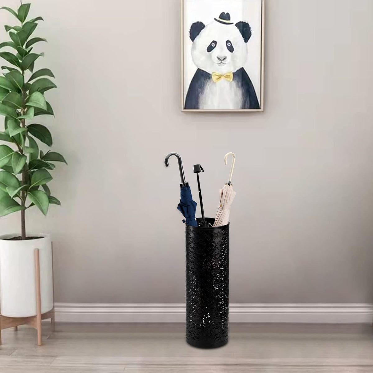 Umbrella stand placed on a floor near a plant and framed art in an entryway