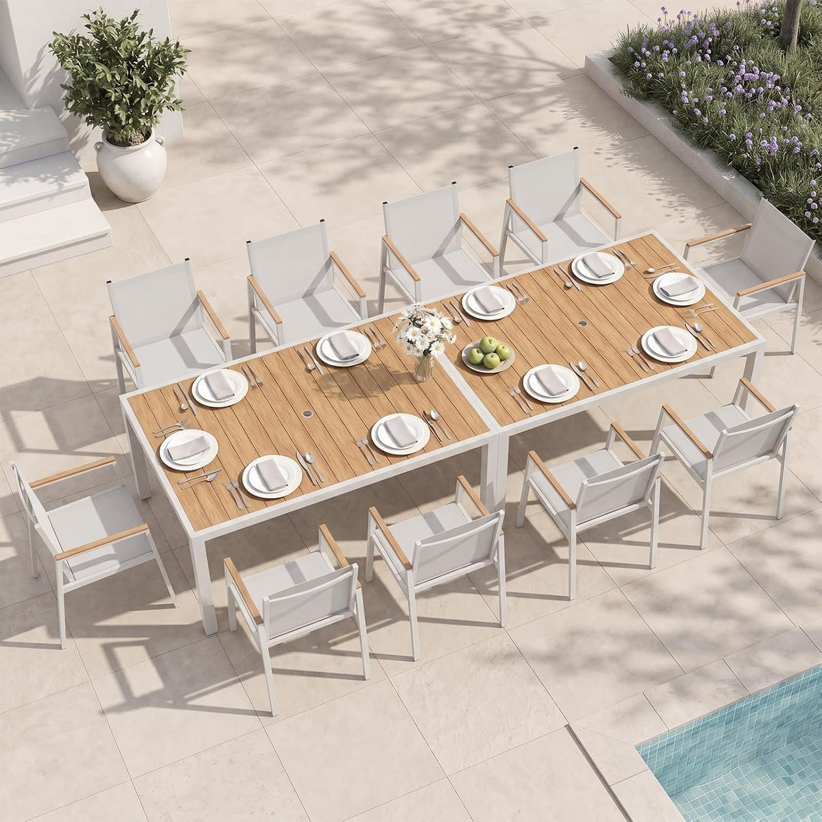 Overhead view of two joined wood-top tables with twelve white-framed armchairs arranged for dining.
