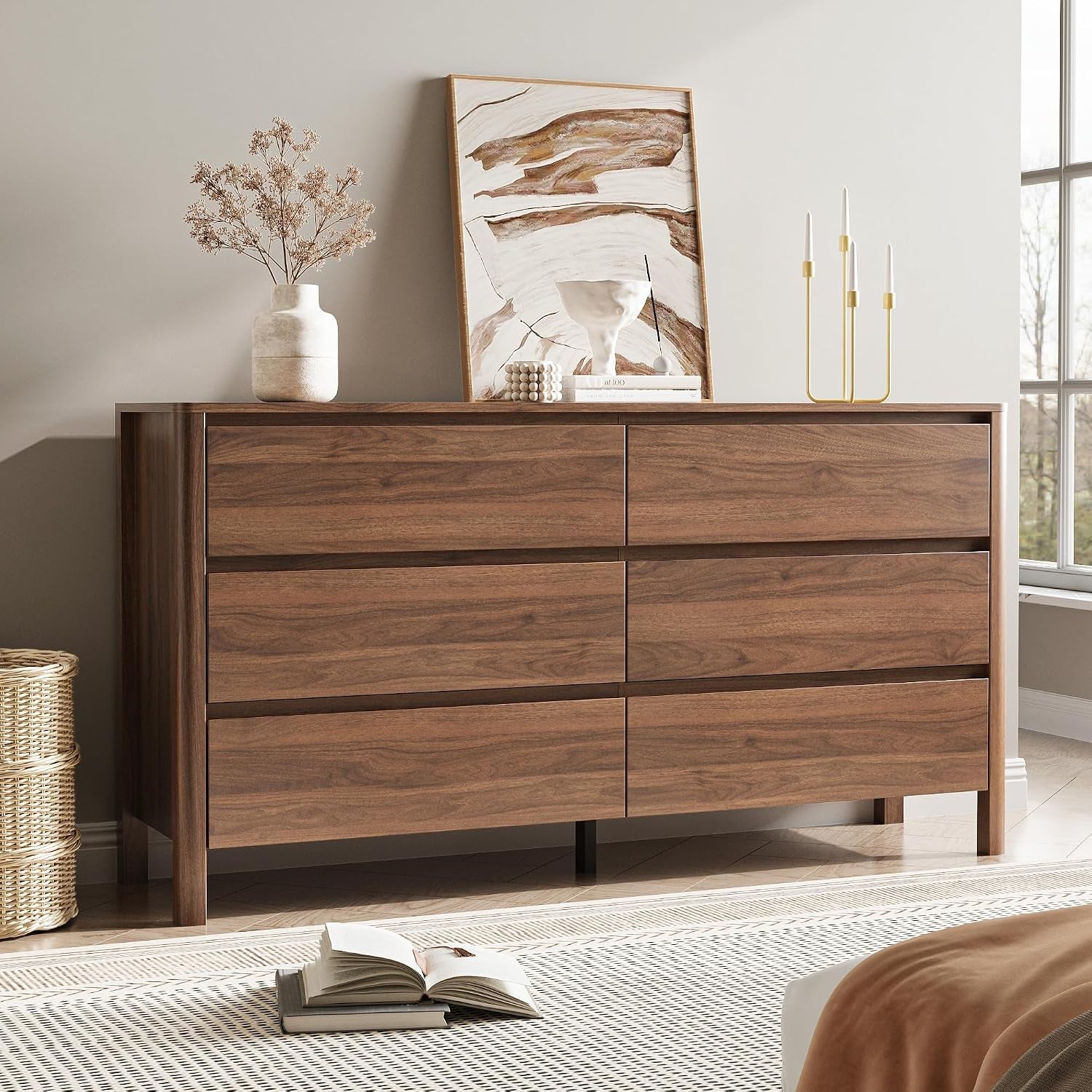 Straight-on view by a bright window showing the walnut dresser with a gold three-candle holder and an open book on the rug.