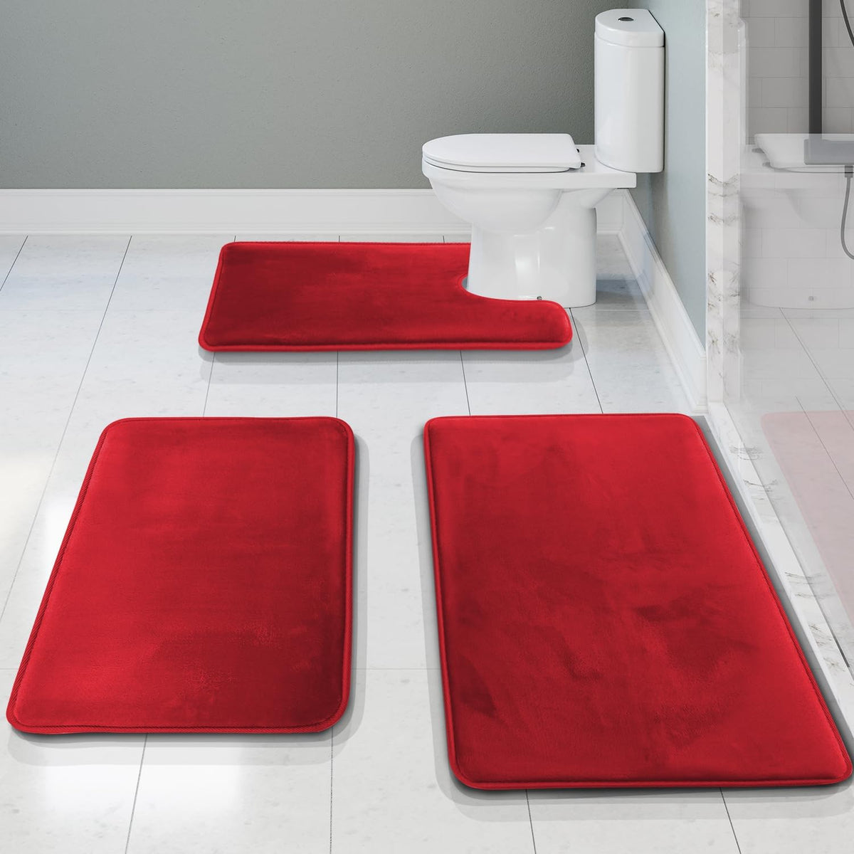 Three bright red bath rugs arranged on white tile, including a U-shaped rug positioned at the toilet base.