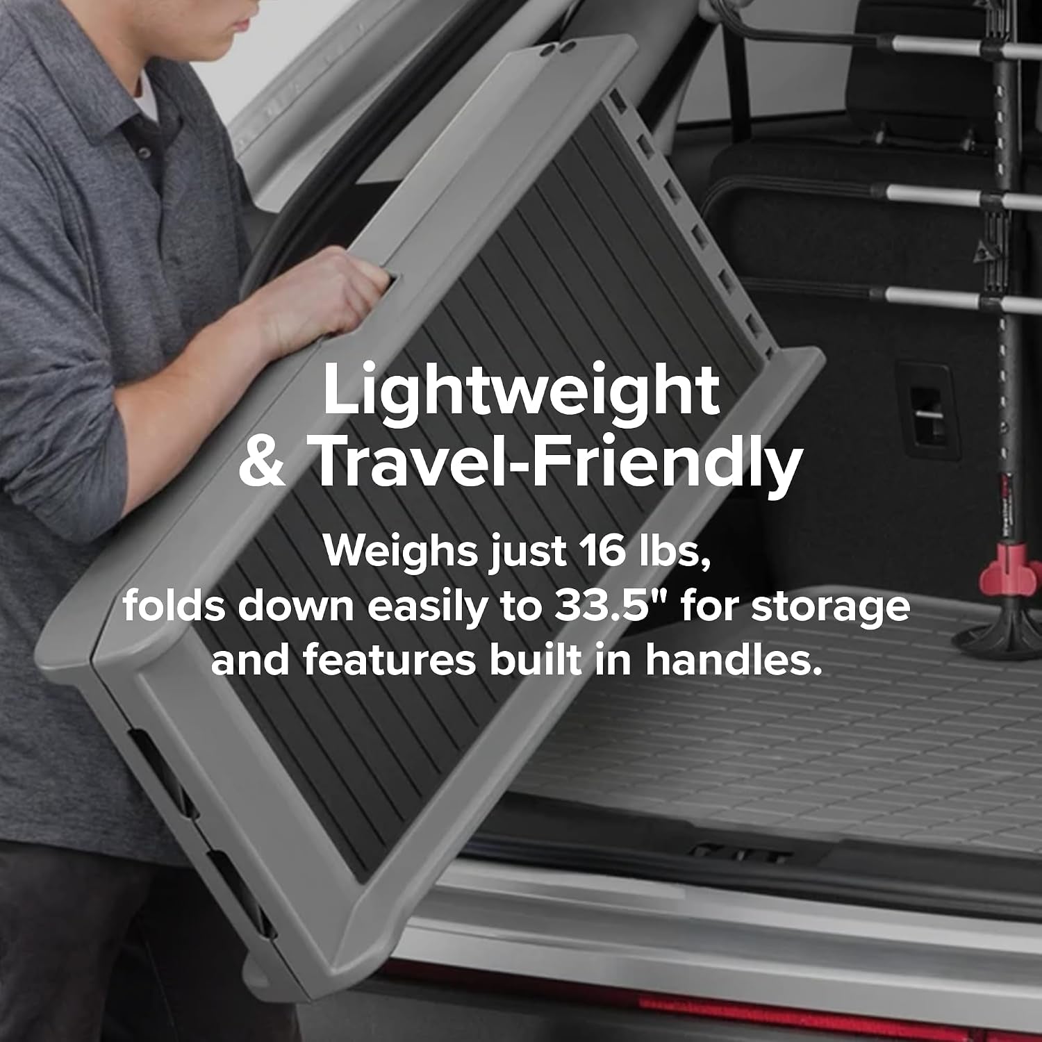 Person lifting the ramp folded in half by its built‑in handle while positioning it into a vehicle cargo area.
