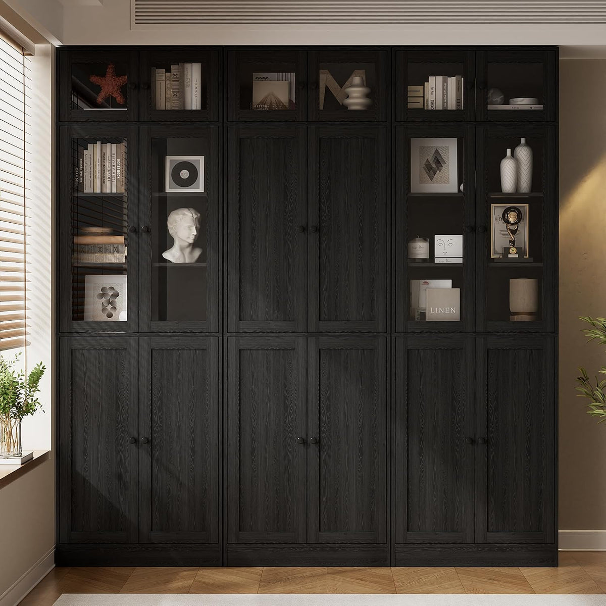 Wide front view of three black bookcase sections with glass upper doors and closed lower cabinets.