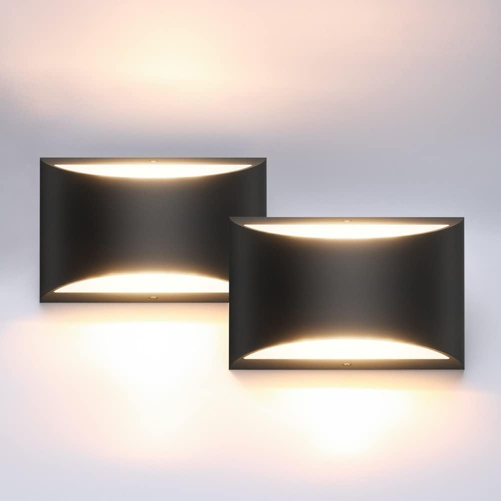 Pair of black wall sconces shown lit, warm light glowing above and below each rectangular fixture.