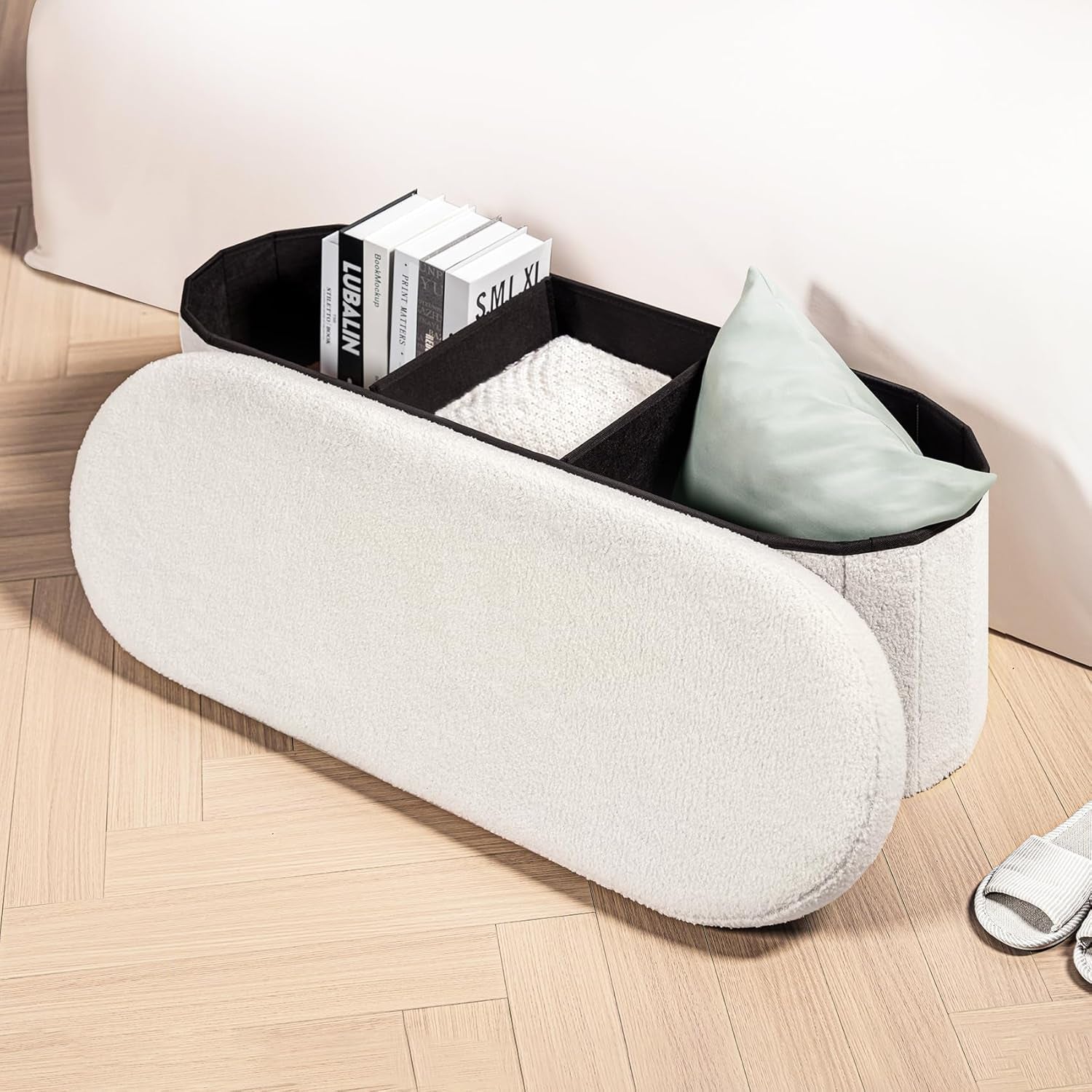 Open ottoman showing three interior storage compartments with books and pillow inside