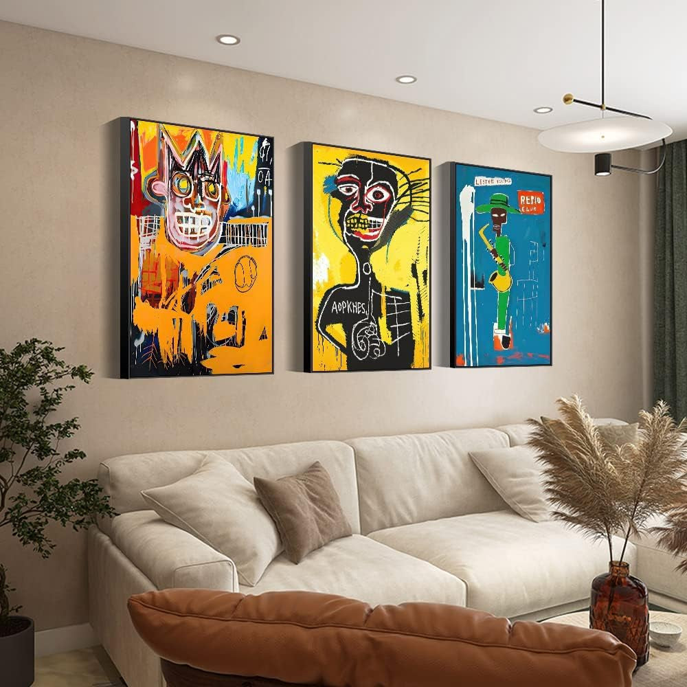 Three tall, colorful framed abstract canvases hung above a beige sofa in a warm living room with a pendant light and pampas