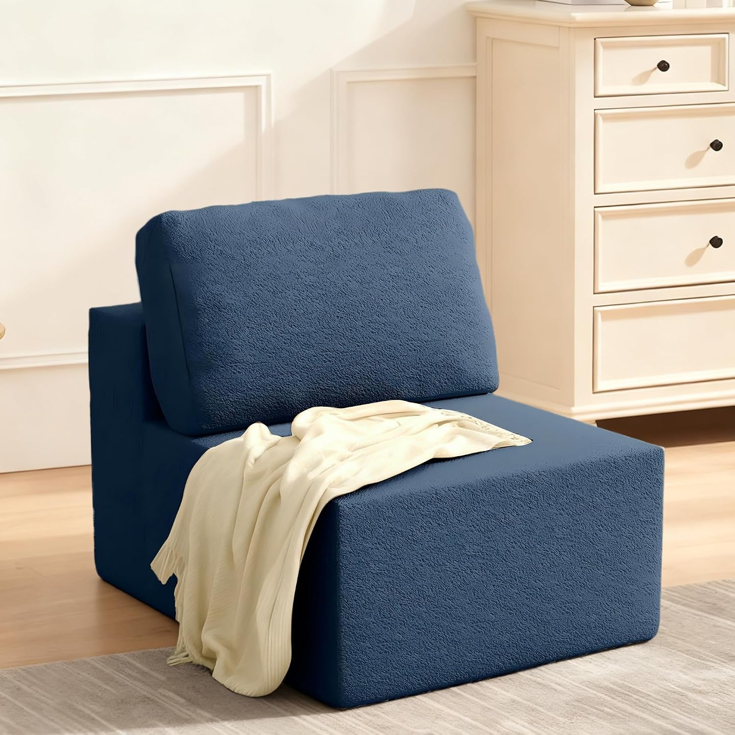 Armless single seating module covered in deep blue fabric with a draped cream throw.