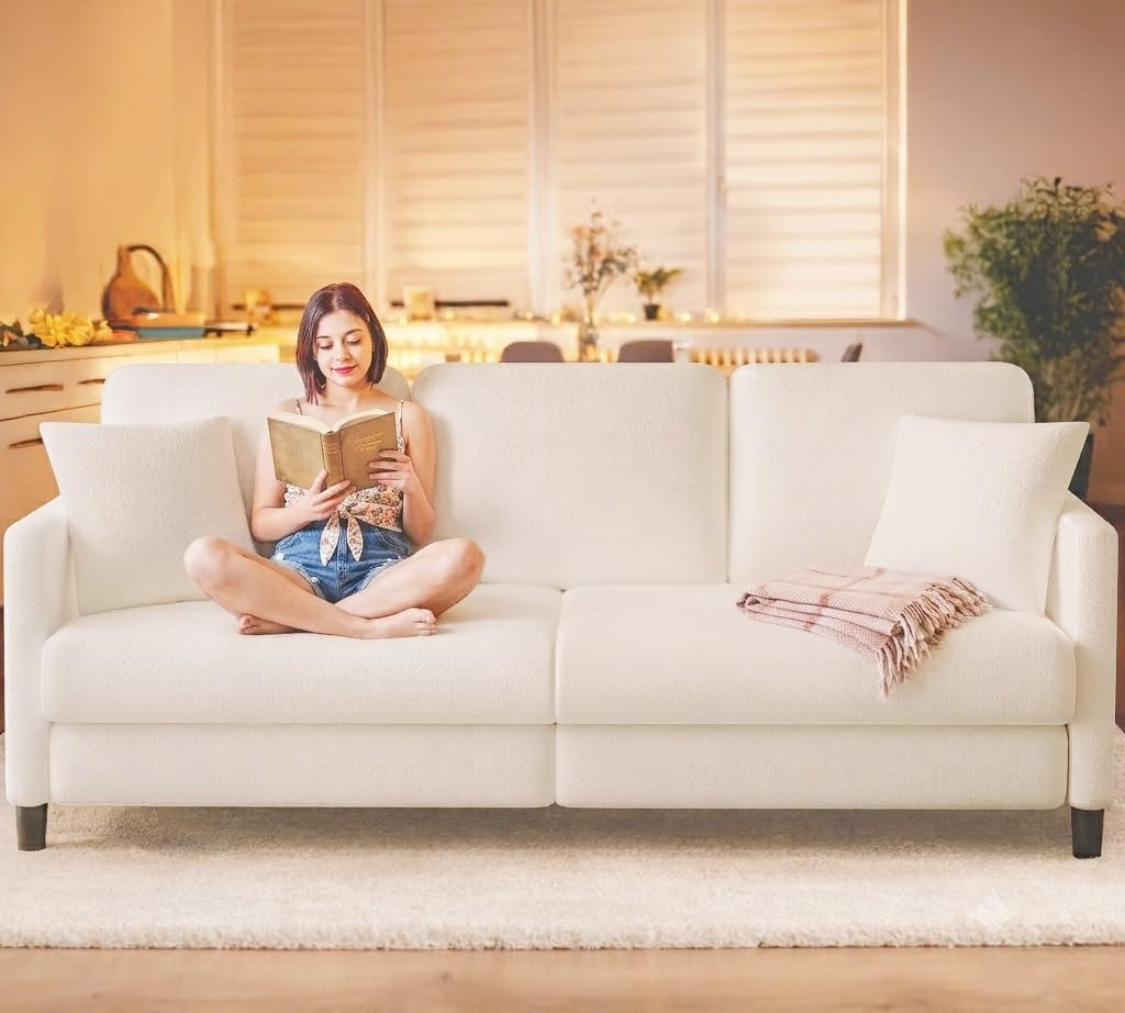 Cream teddy-fleece 83-inch sofa front view in living room with a person sitting cross-legged reading