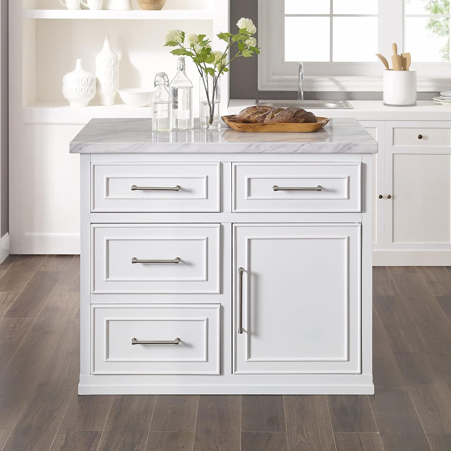 Front-centered close view of a white kitchen island showing three stacked drawers, a single door with a long bar pull and