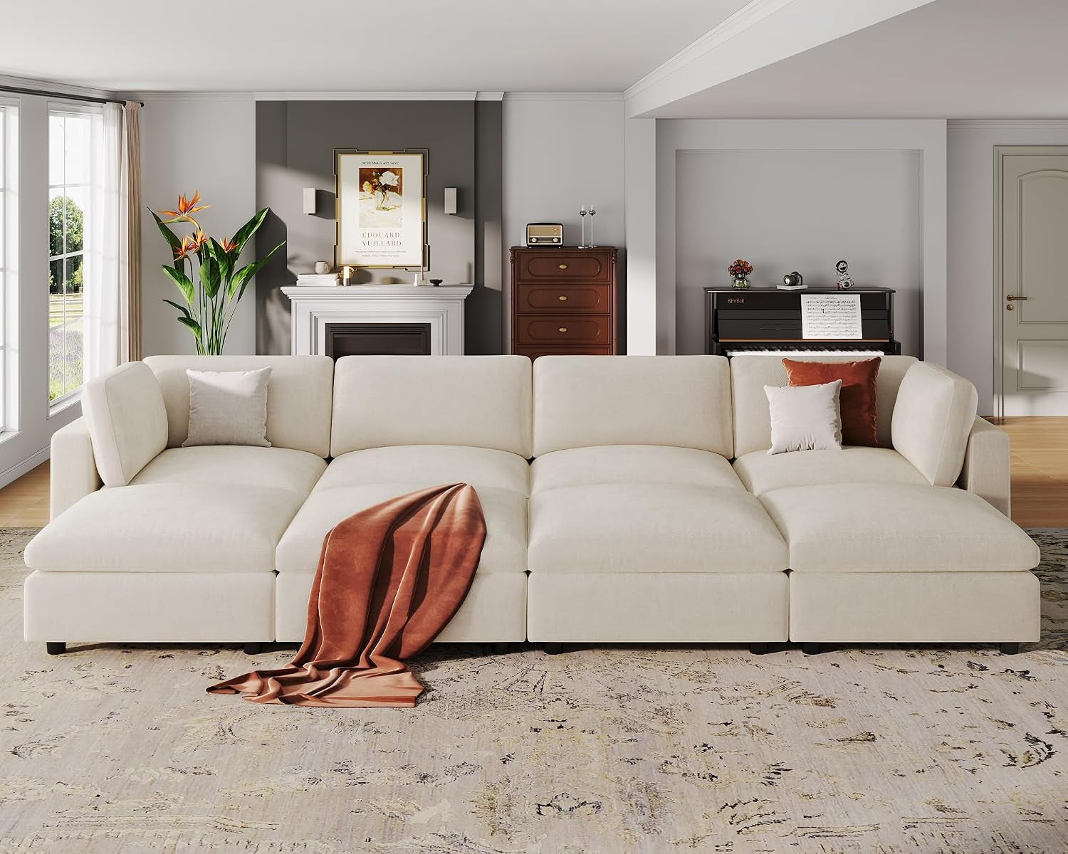 Front-facing view of a low-profile cream sectional arranged as four wide seats with throw pillows and a draped rust throw.