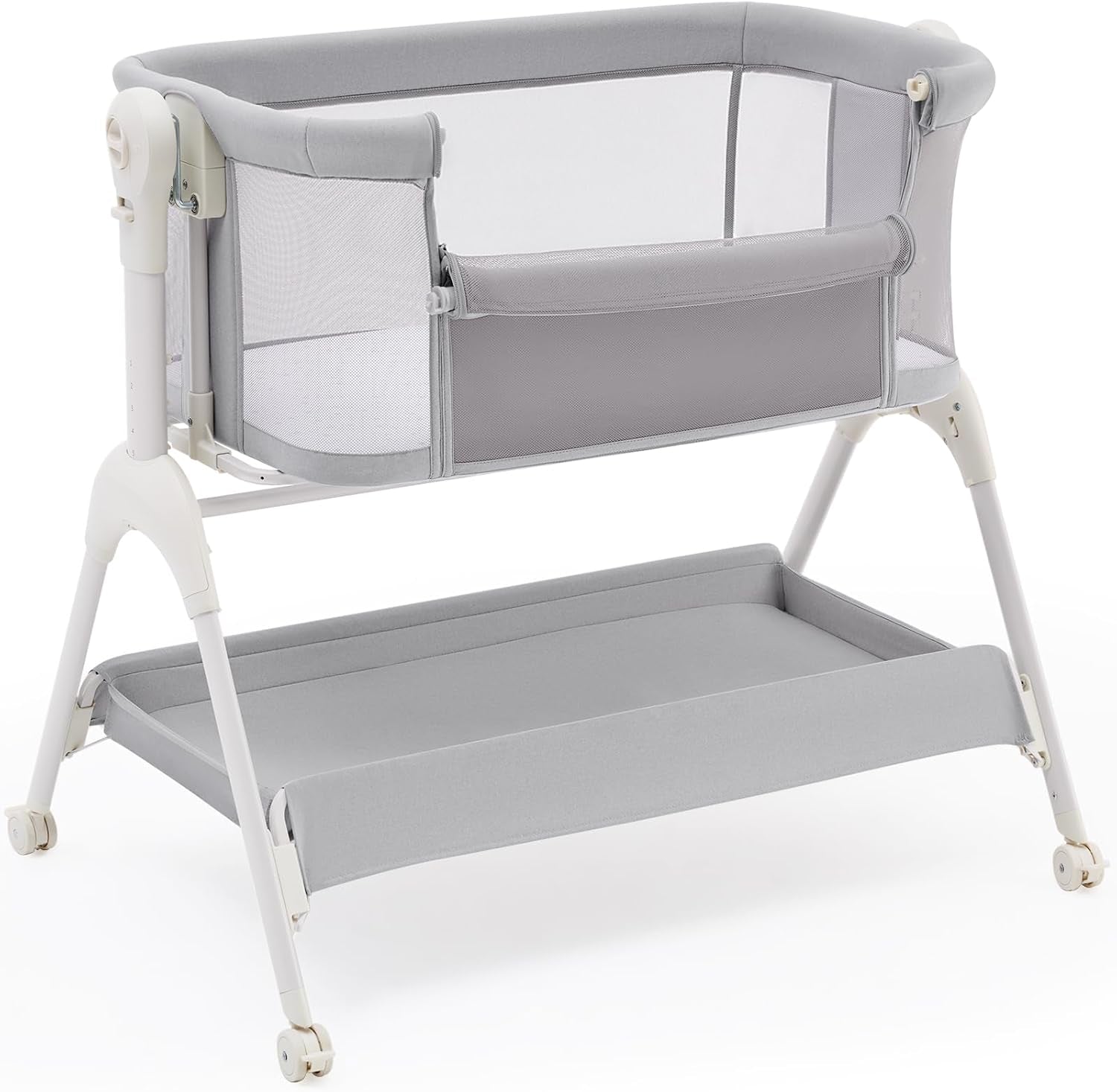 Light gray bedside bassinet on a white frame with mesh sides and a matching fabric storage shelf underneath.