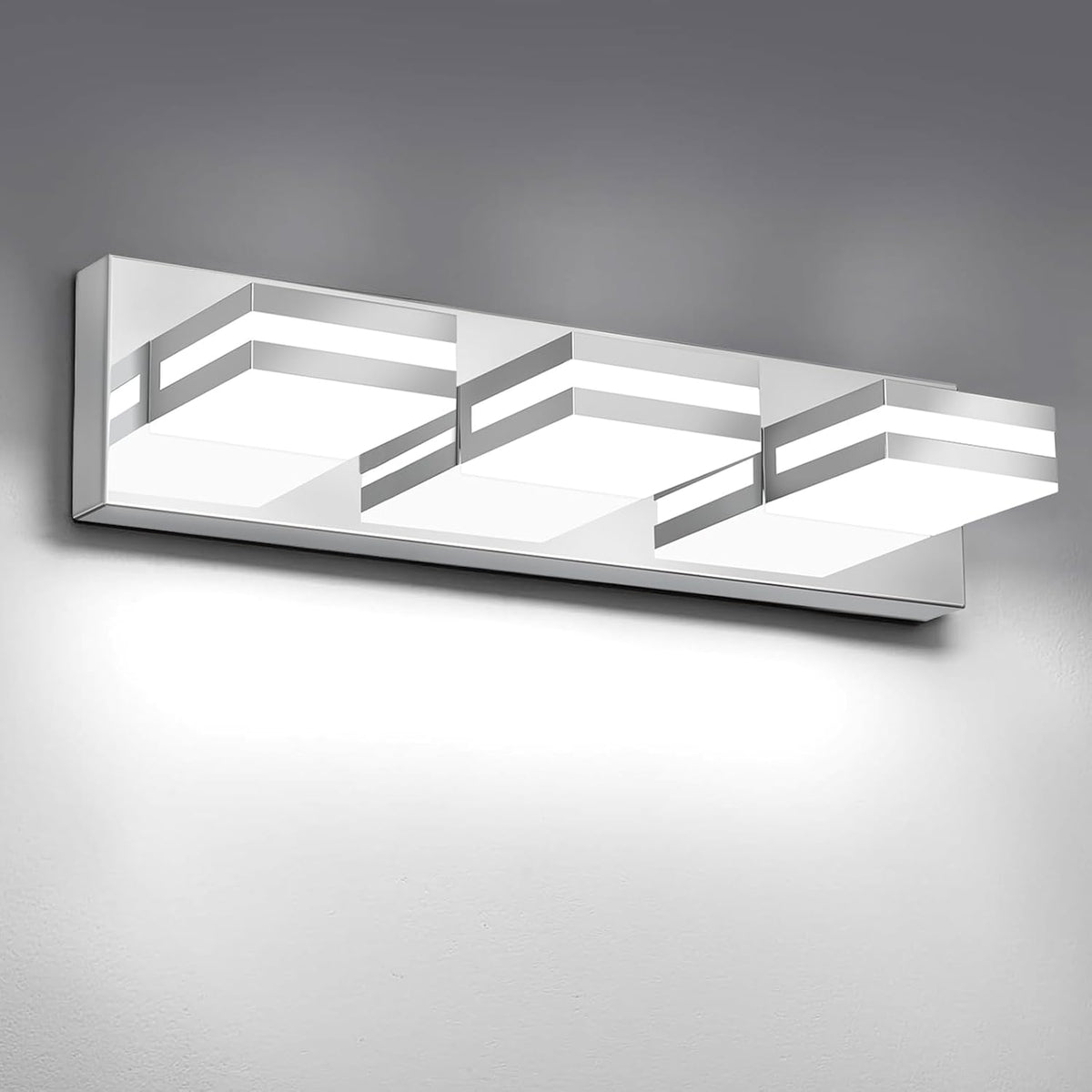 Close angled view of a four-light rectangular LED vanity fixture in polished silver finish on a gray wall.