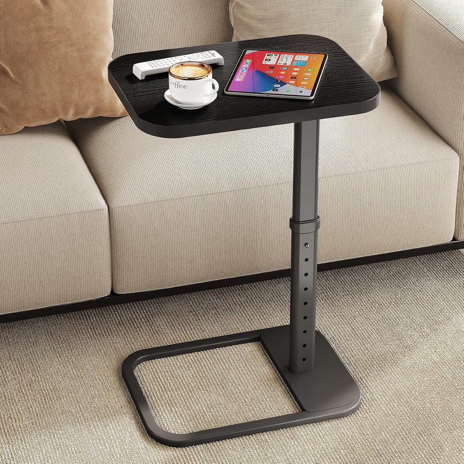 Black metal C-table with dark wood top beside a beige sofa holding a tablet and coffee cup.