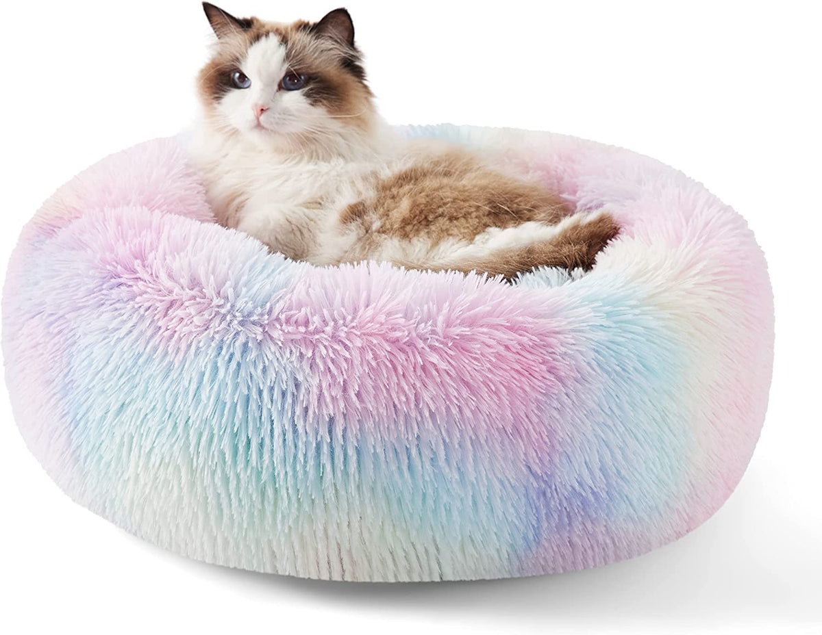 Three-quarter view of a pastel multicolor fluffy donut bed holding a relaxed ragdoll cat.