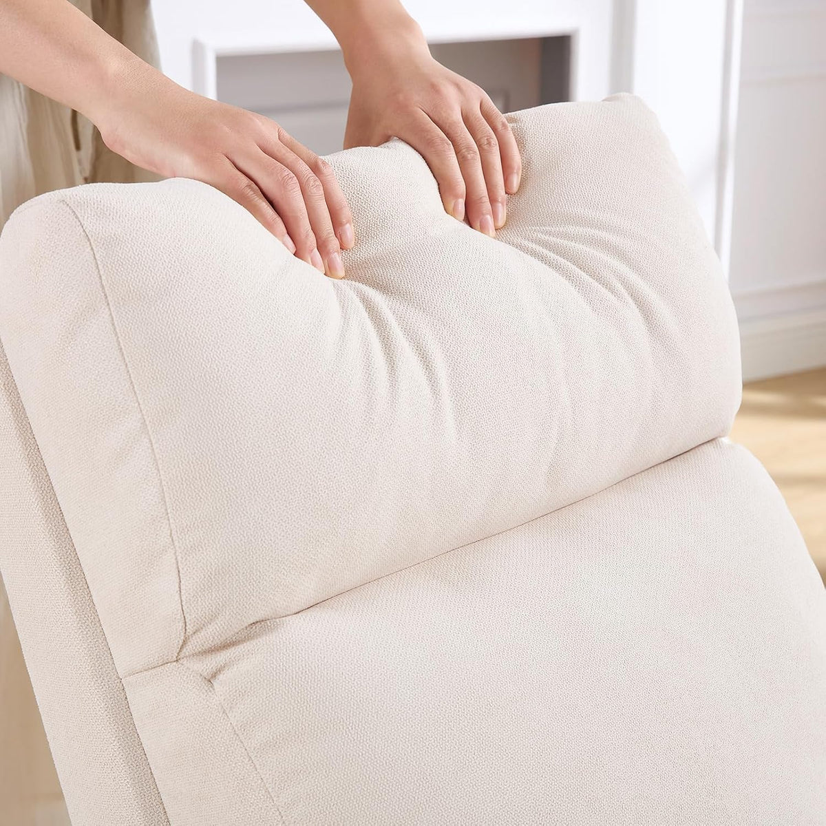 Close-up of hands pressing the padded beige headrest of the chair.