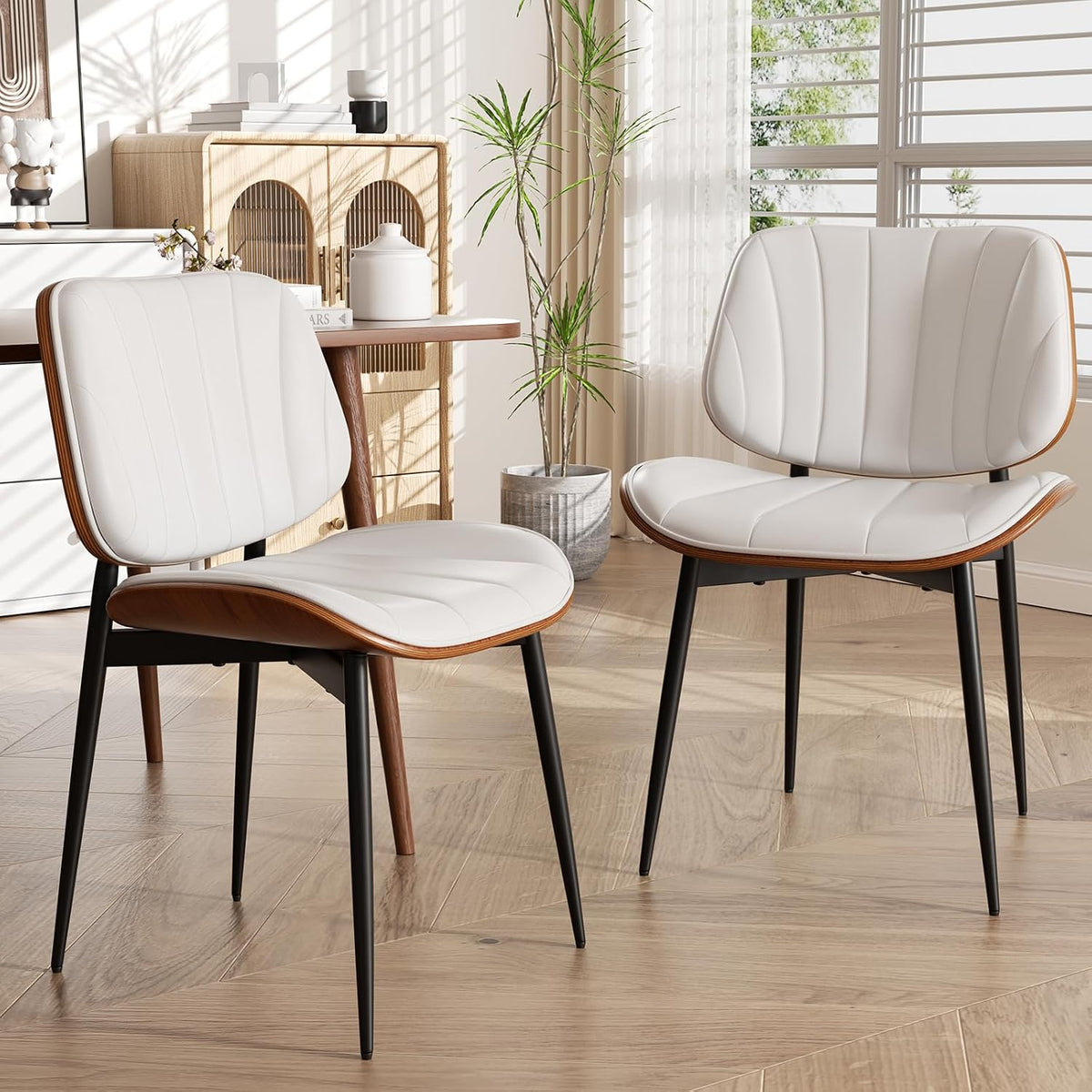 Close view of two chairs showing white faux leather seats, walnut bentwood edge and black tapered legs