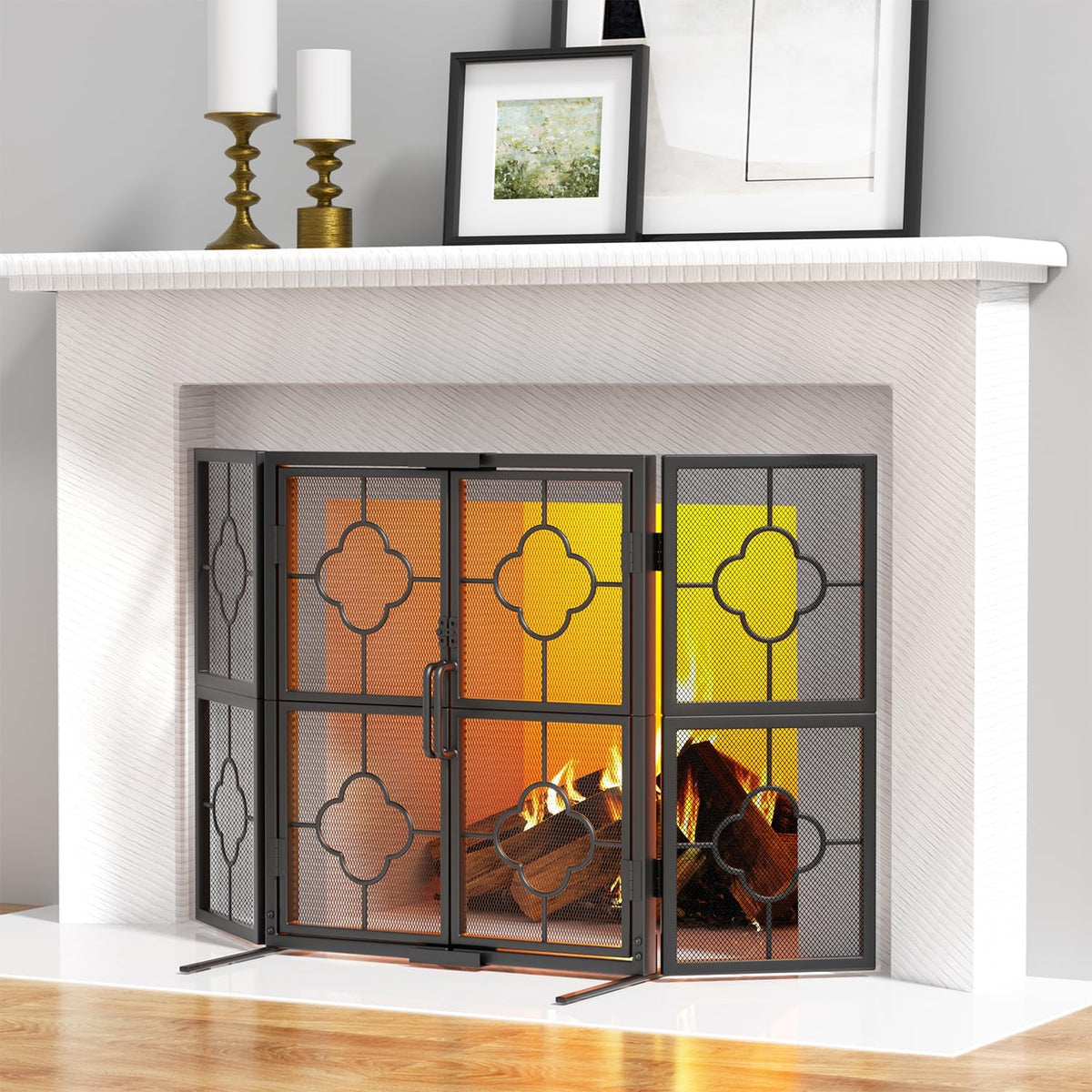 Front view of a black four-panel metal fireplace screen with decorative quatrefoil panels installed in a white fireplace
