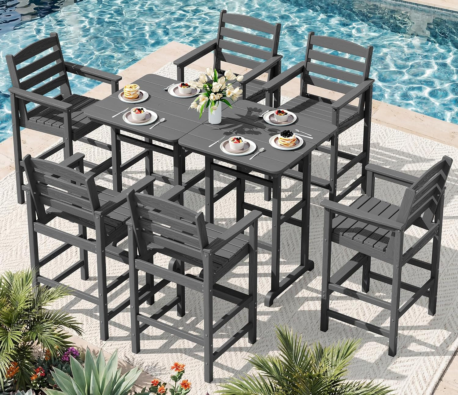 Six-seat bar table set arranged on a rug next to a pool, chairs and table in dark gray.