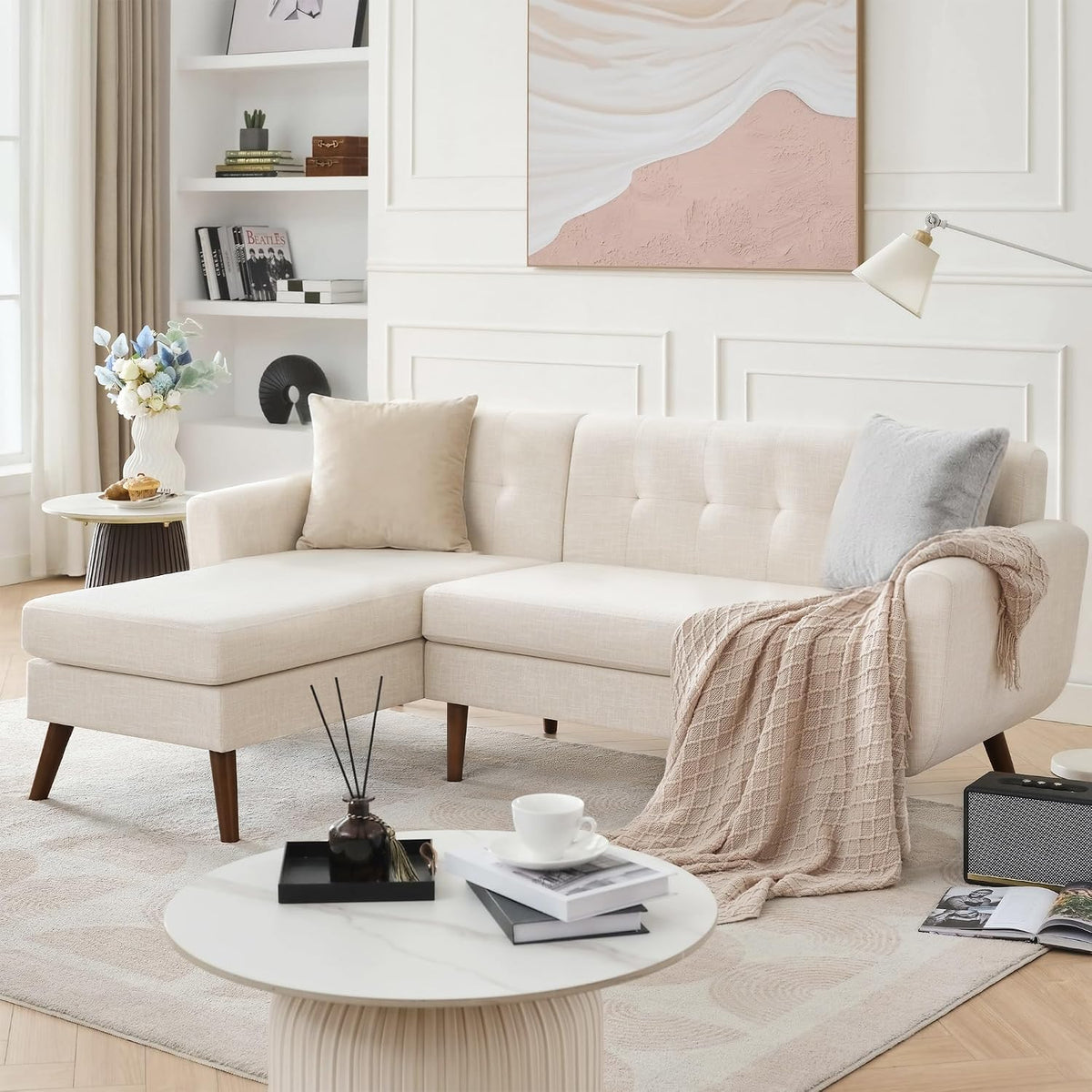 Cream-colored tufted sectional with chaise, pillows and throw in styled living room