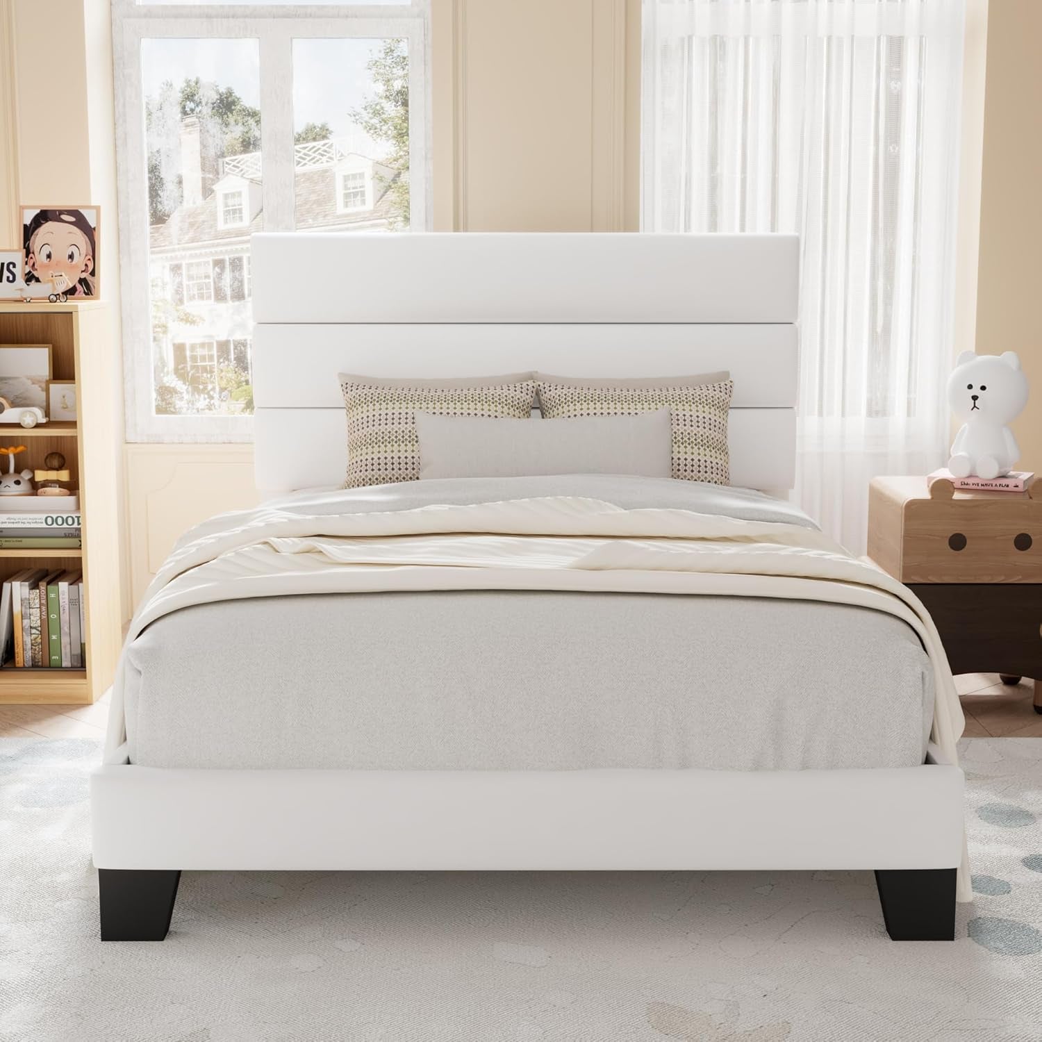Front view of a white upholstered bed with a three-panel headboard in a softly lit child's room.
