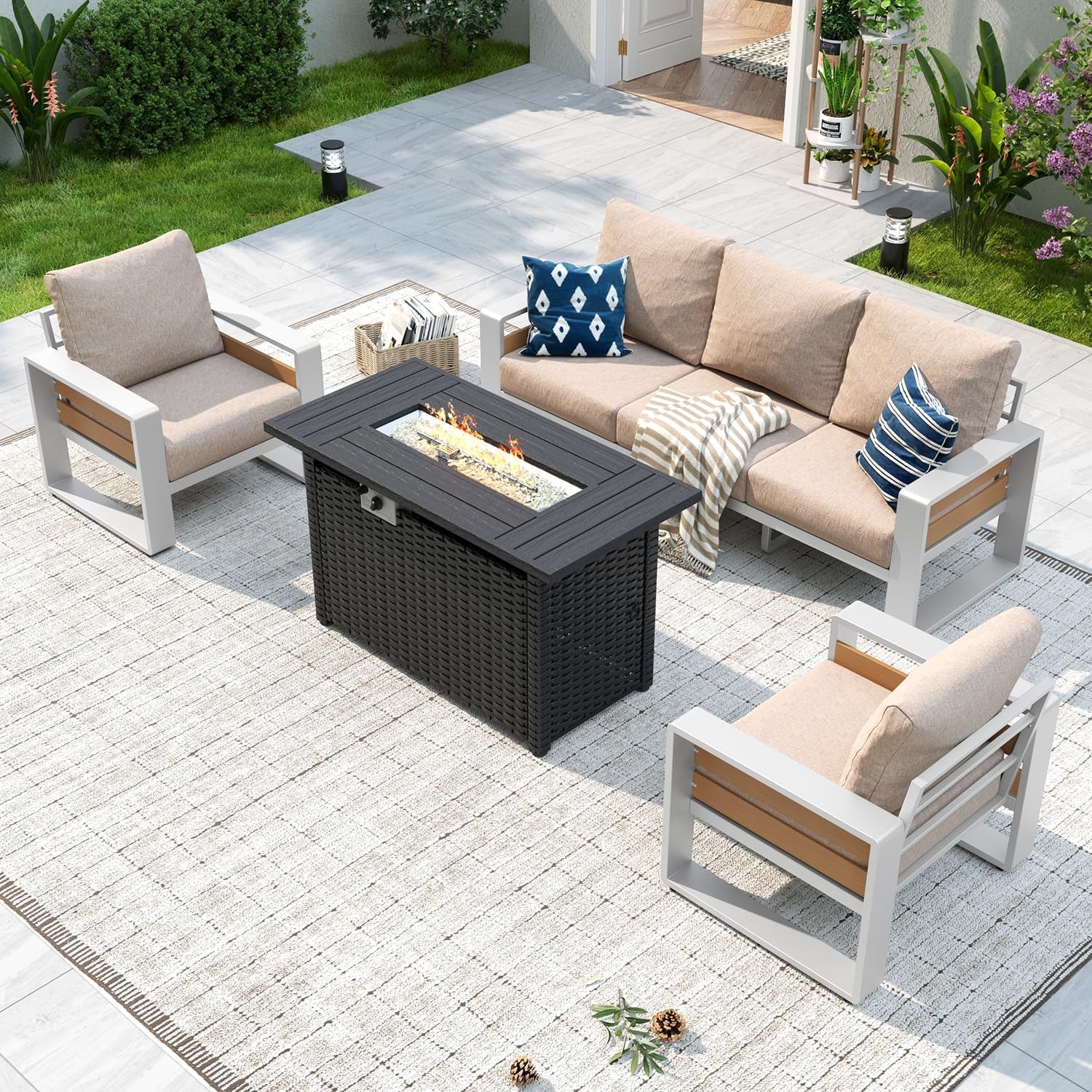 Patio set with white-framed seating and beige cushions centered around a black fire-pit table on a tiled patio.