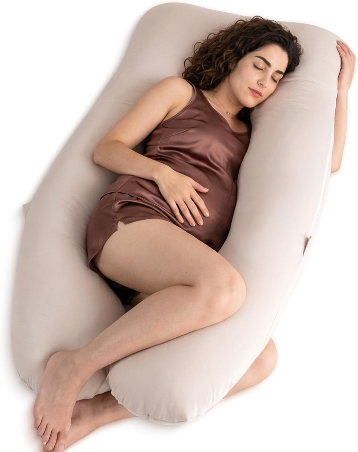 Angled view of a pregnant woman resting inside a light beige U-shaped full body pillow