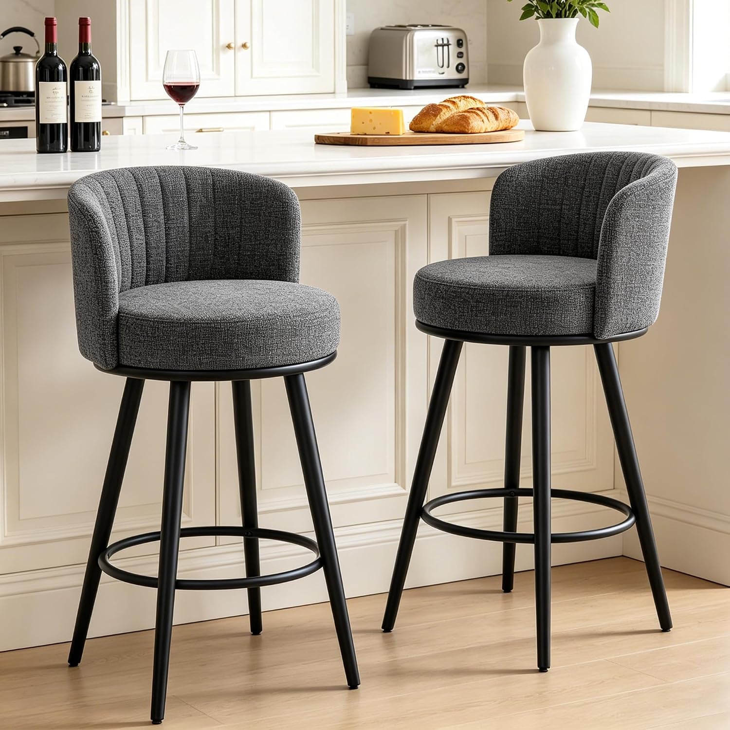 Close frontal view of two dark-gray swivel bar stools showing rounded backs and circular footrests at a kitchen counter