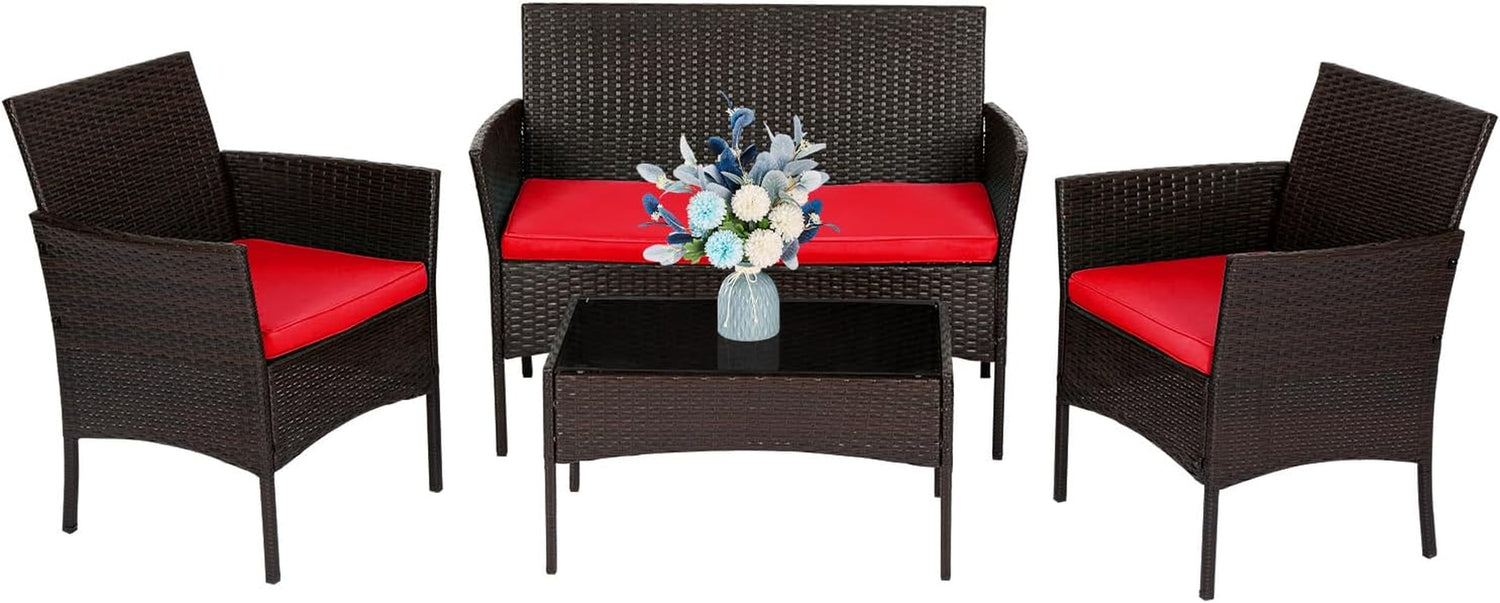Dark brown woven rattan loveseat and two chairs with red cushions and a rectangular glass-top coffee table, flowers on table.