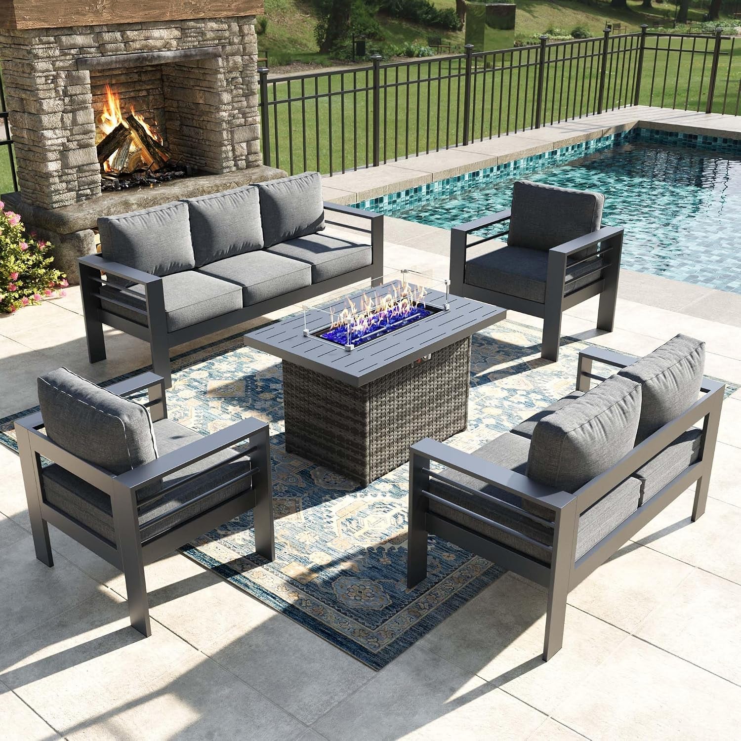 Aerial view of dark gray seating arranged around a rectangular fire pit on a patio rug.
