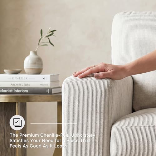 Close-up of a hand pressing the chenille arm upholstery to show fabric texture and weave in stone color