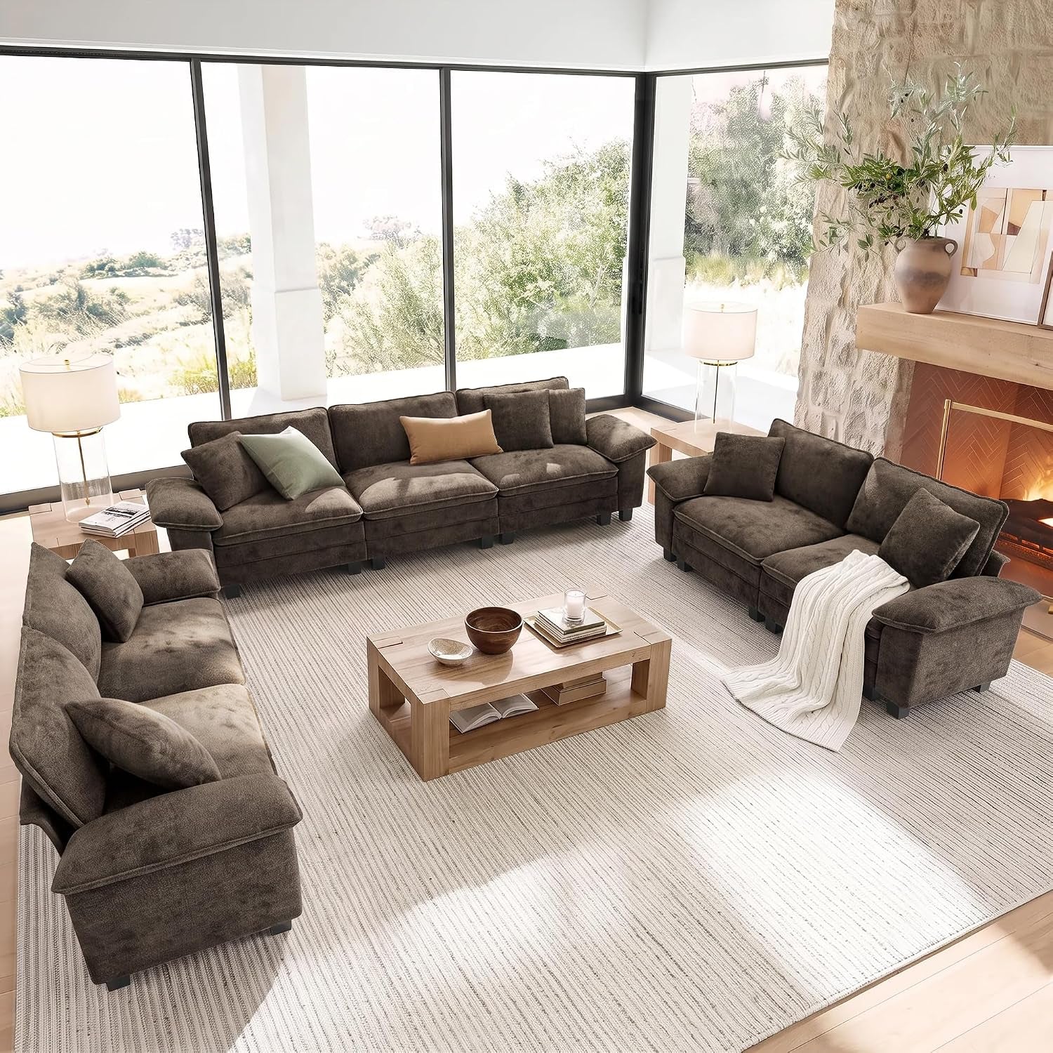 Deep brown three-seat sofa and loveseat set around a wooden coffee table beside a stone fireplace