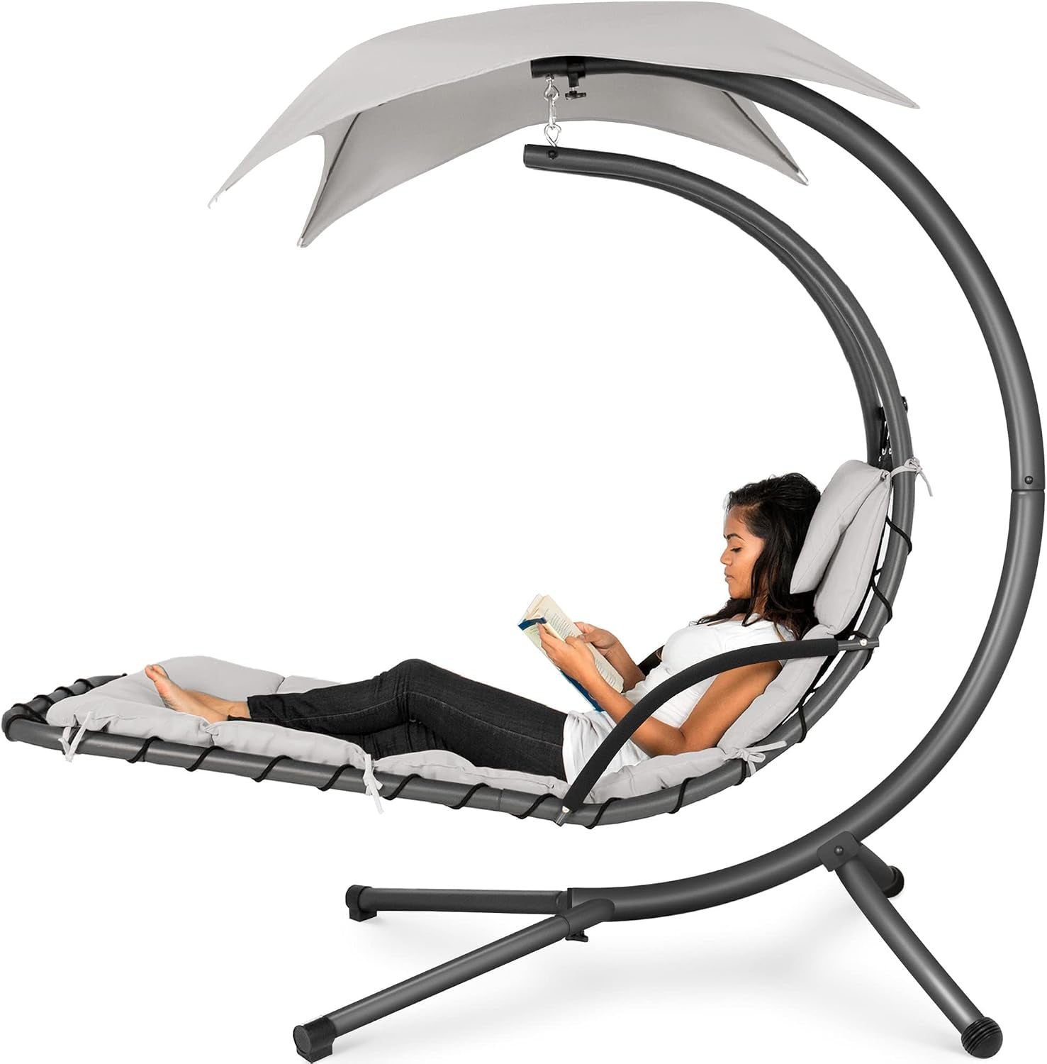 Side view of the same curved hanging chaise in light gray cushions and canopy with a woman reading.