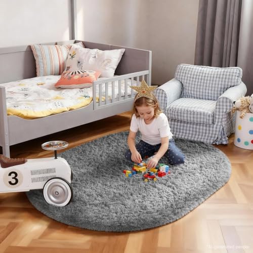 Child playing with blocks on a small oval gray shag rug beside a toddler bed and armchair