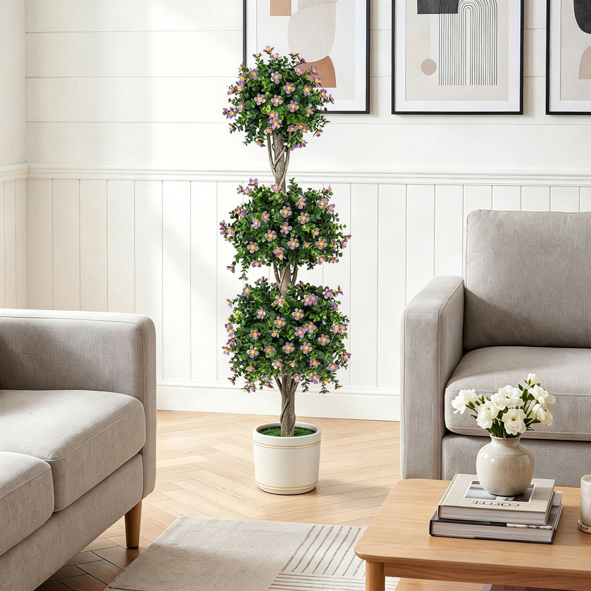 Flowering three-ball topiary displayed between two armchairs in a light living room.