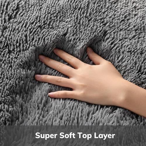 Close-up of a hand pressing into dense, long-pile gray rug fibers to show softness