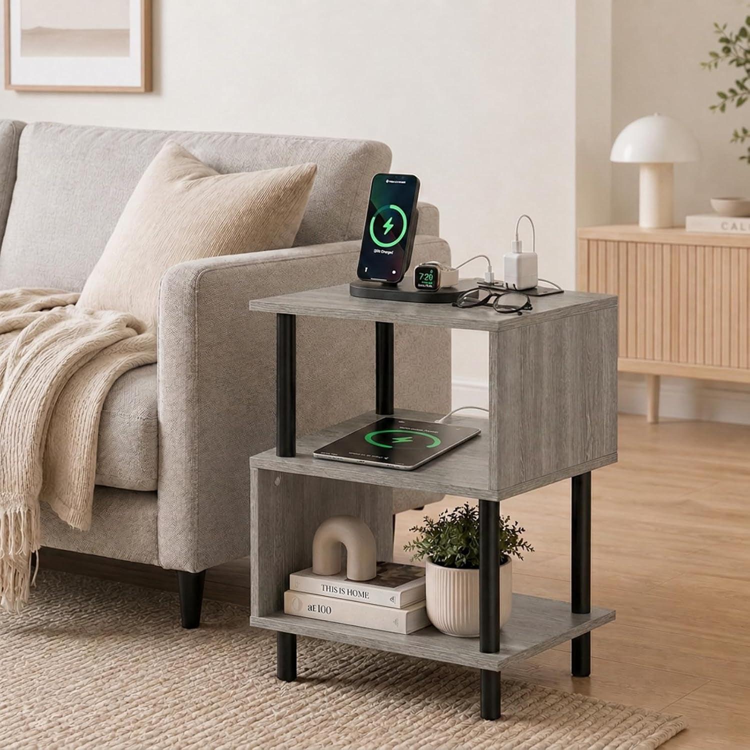 Three-tier rustic brown side table with black metal legs next to a light gray sofa in a living room.