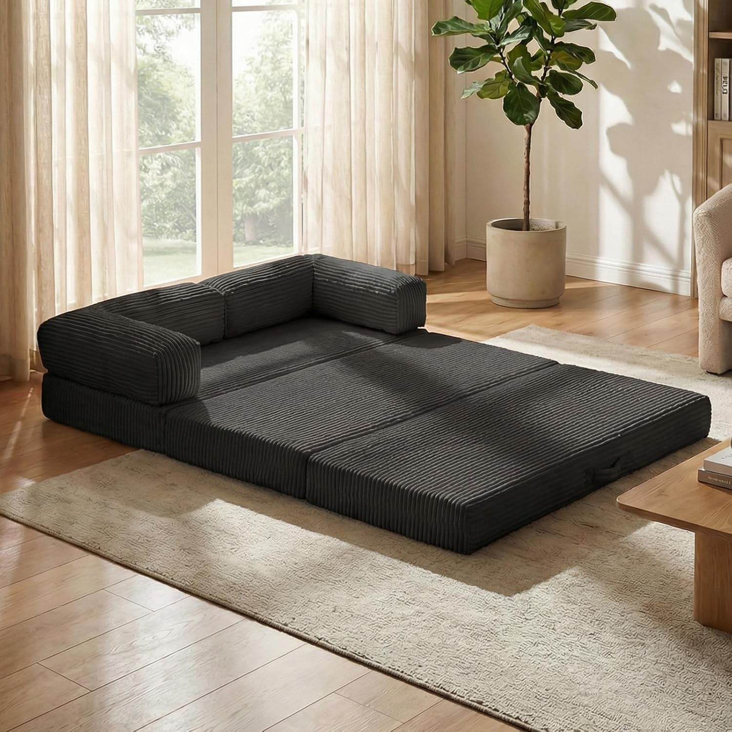 Dark grey tri-fold mattress unfolded flat on a rug with two armrest cushions positioned as a low back.