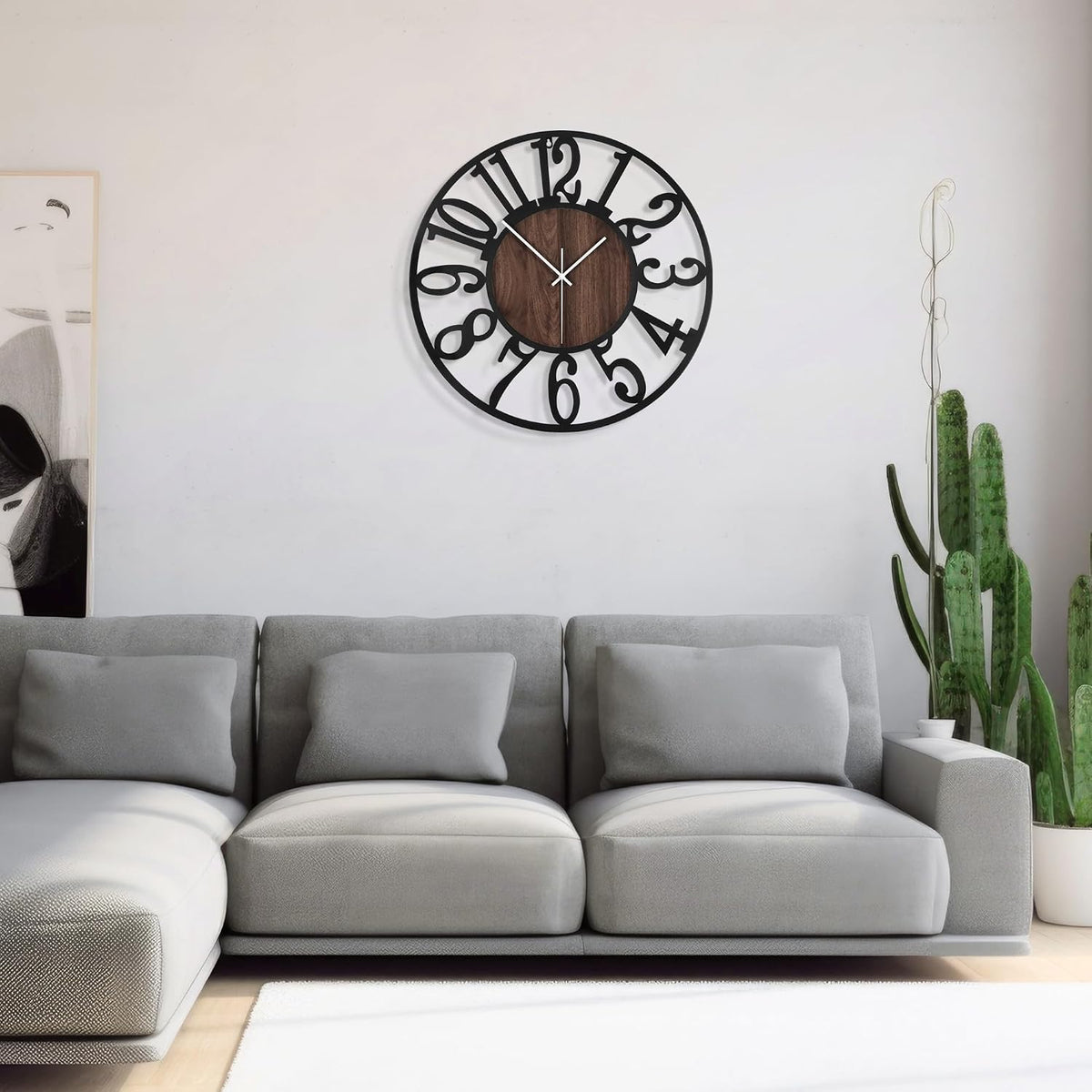 Centered view of the clock on a pale wall above a gray sofa and a tall cactus plant
