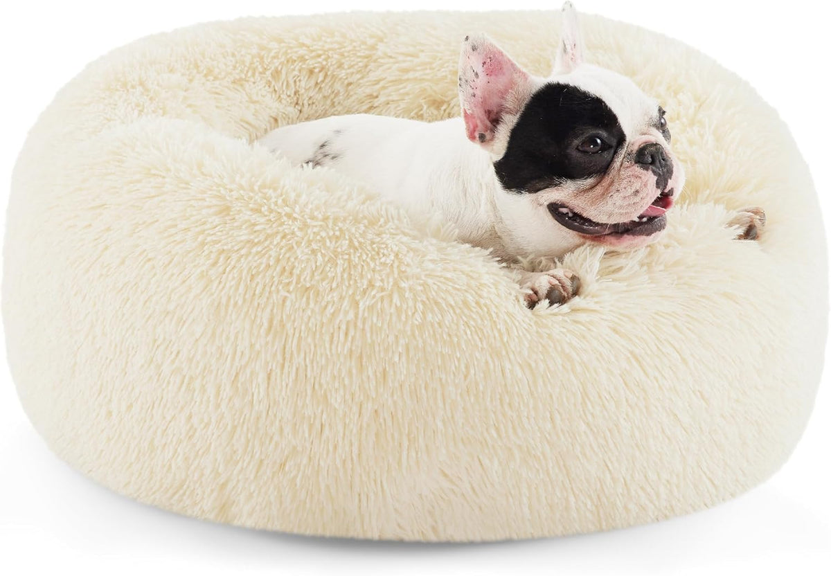 Front view of a cream-colored faux-fur donut bed with a black-and-white French bulldog nestled inside.