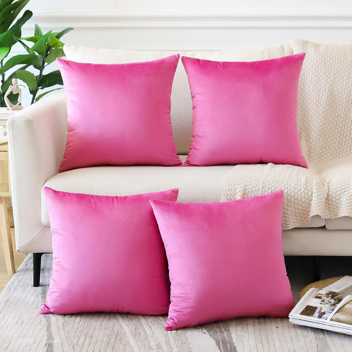 Bright pink square and rectangular pillow covers arranged on a neutral sofa and rug.