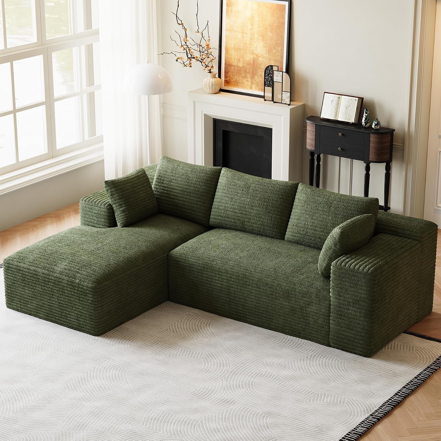 Olive green L-shaped modular sofa with chaise styled in a bright living room by a window.