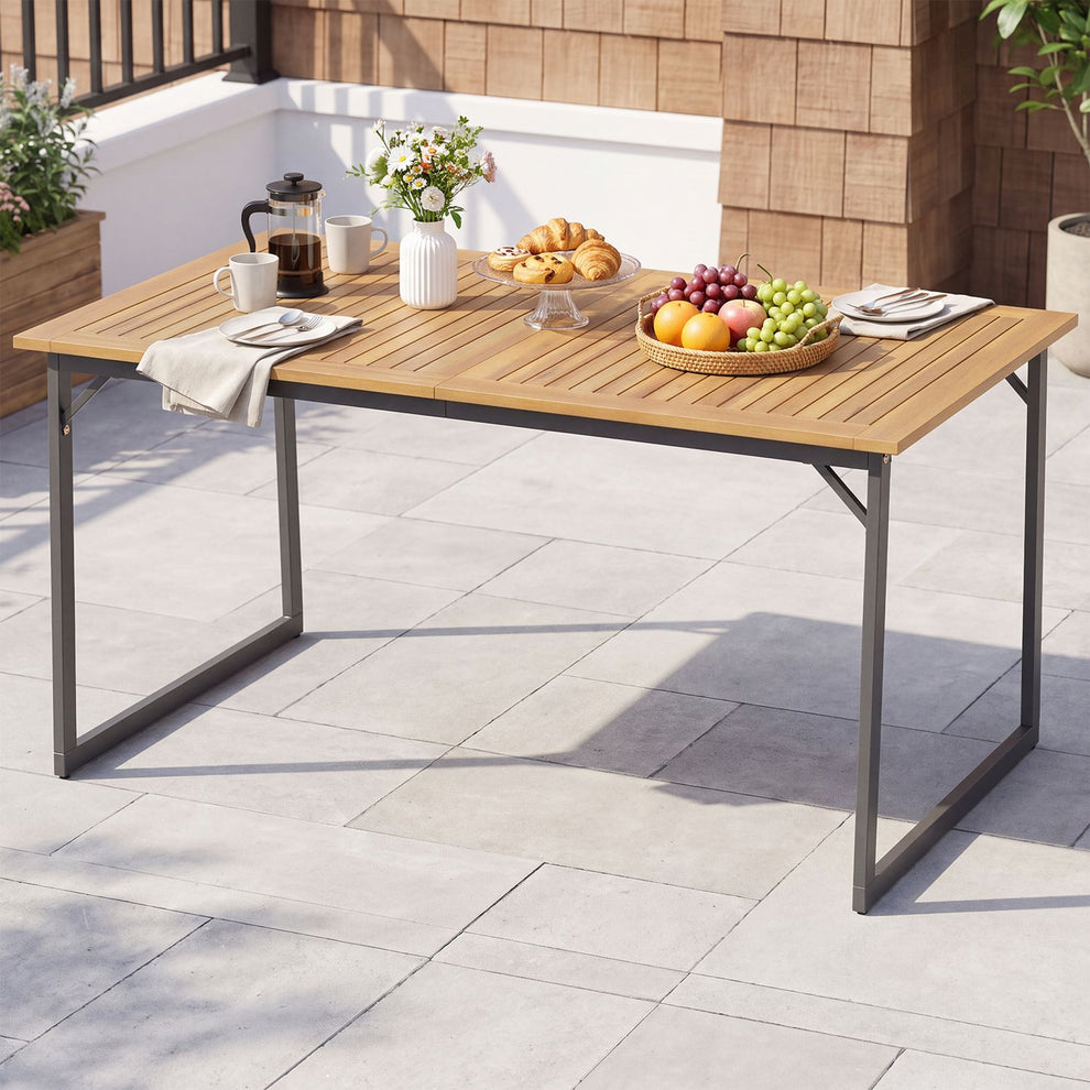 Slatted wooden patio table with dark metal legs, set with fruit, flowers, coffee and pastries.