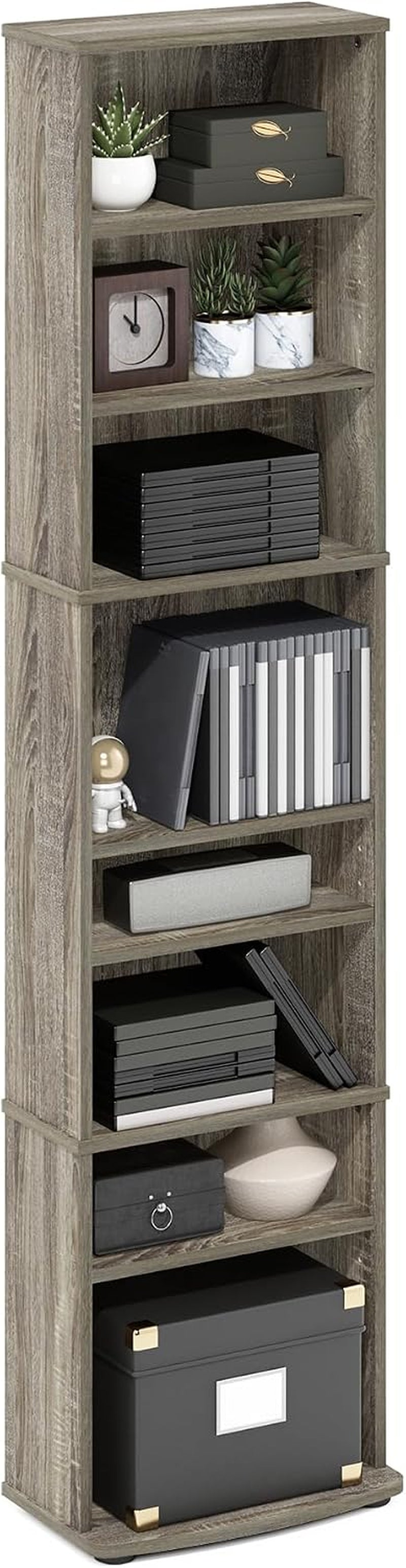 Angled full-height view of a narrow weathered-gray wood media tower staged with boxes, DVDs, plants and small decor.