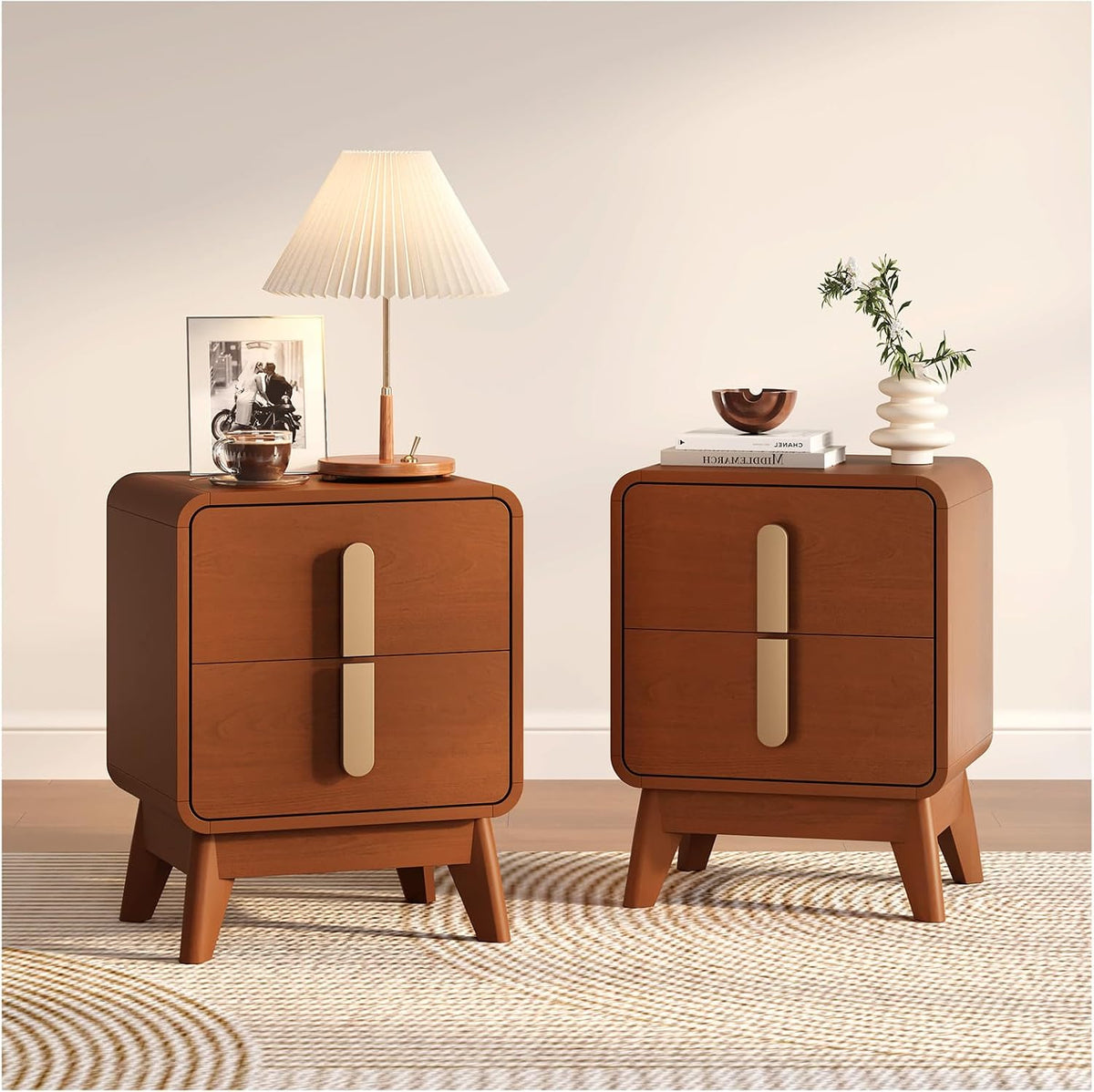 Two rounded-corner medium wood nightstands with vertical gold handles, topped with a pleated lamp, framed photo, bowl and