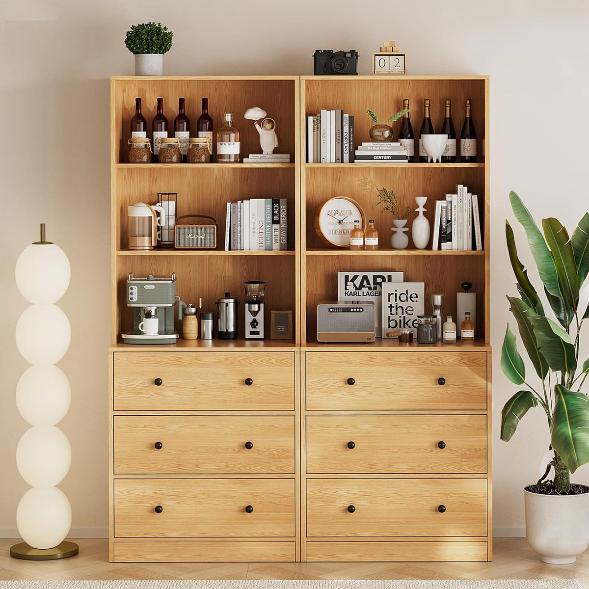 Front view of two tall wood bookcase modules with six drawers and open shelves, styled with decor and plants.