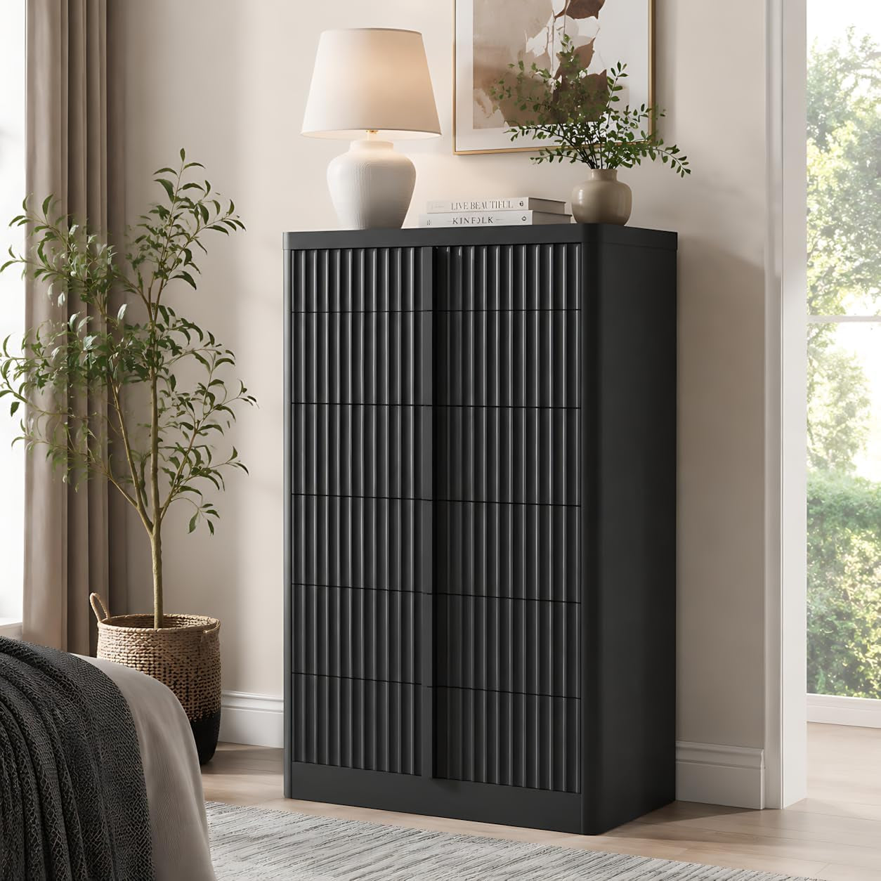 Tall black fluted cabinet against a wall, topped with lamp and decor beside a window
