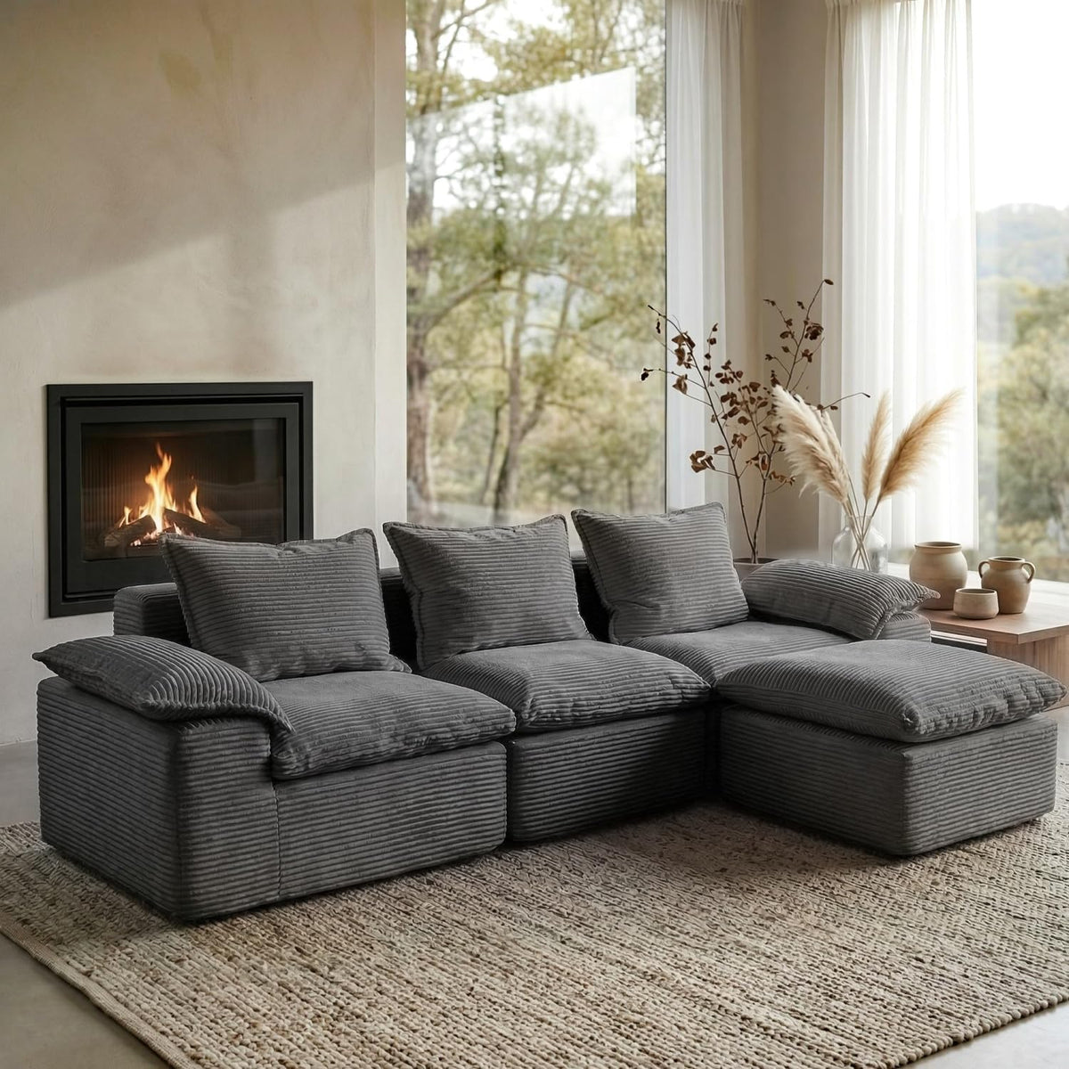 Gray ribbed modular L-shaped sectional sofa arranged on a textured rug beside floor-to-ceiling windows.