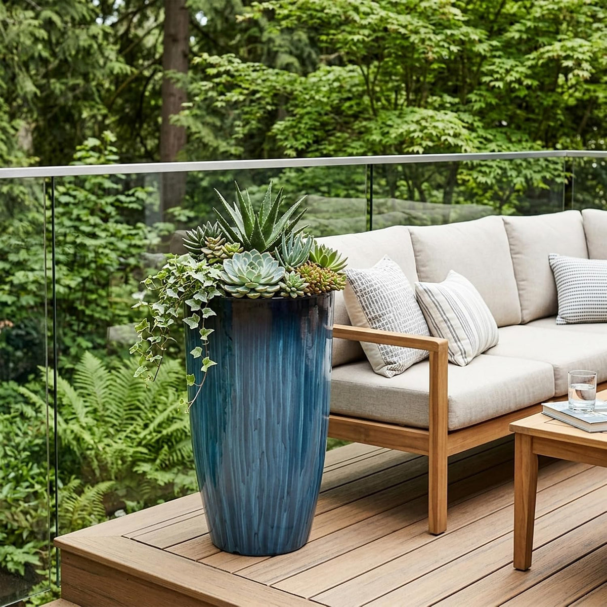 Front three-quarter view of a tall glossy blue gradient planter on a wooden deck filled with succulents beside a beige