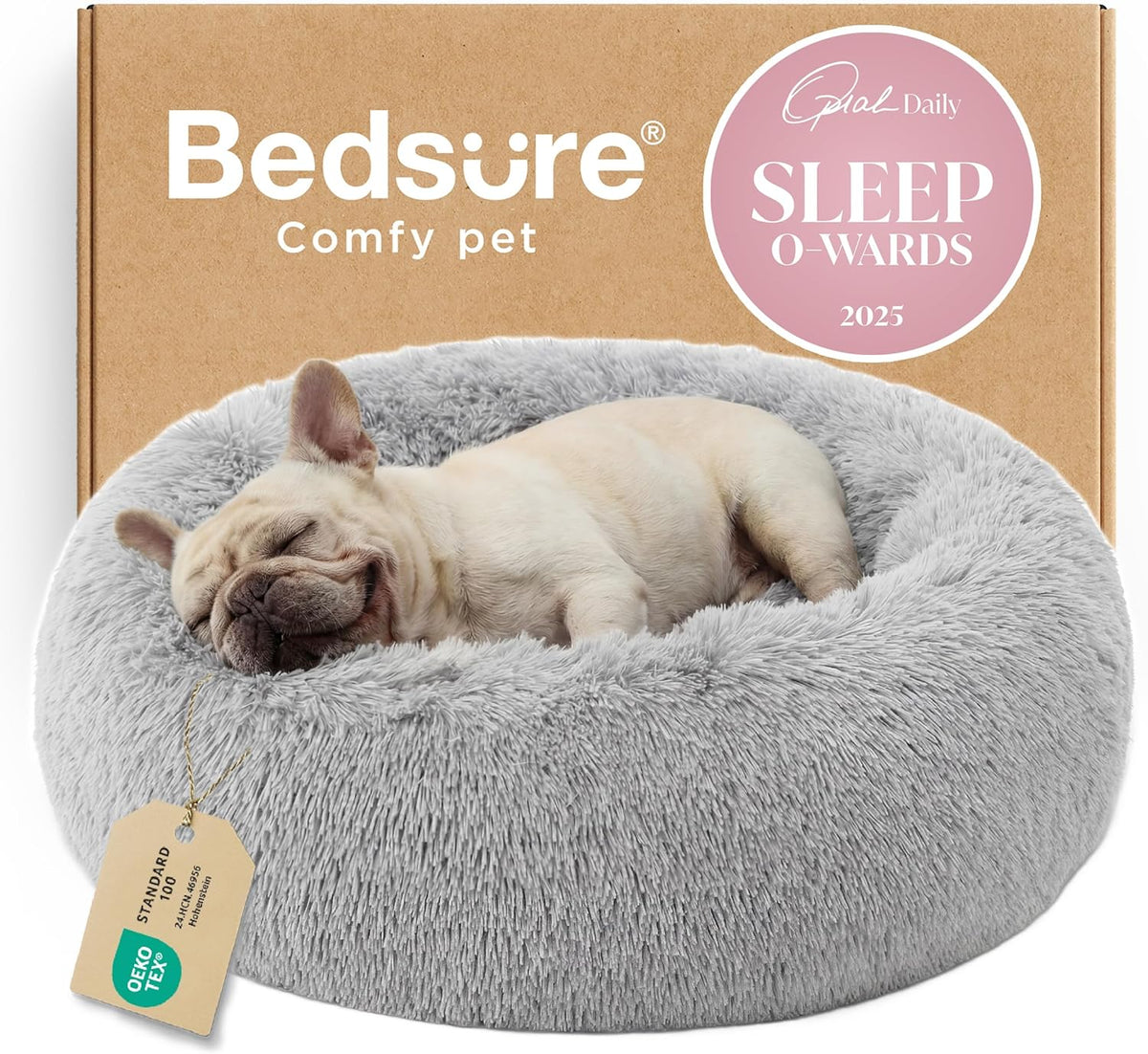 Light gray round faux-fur donut dog bed with a sleeping dog in front of a cardboard box